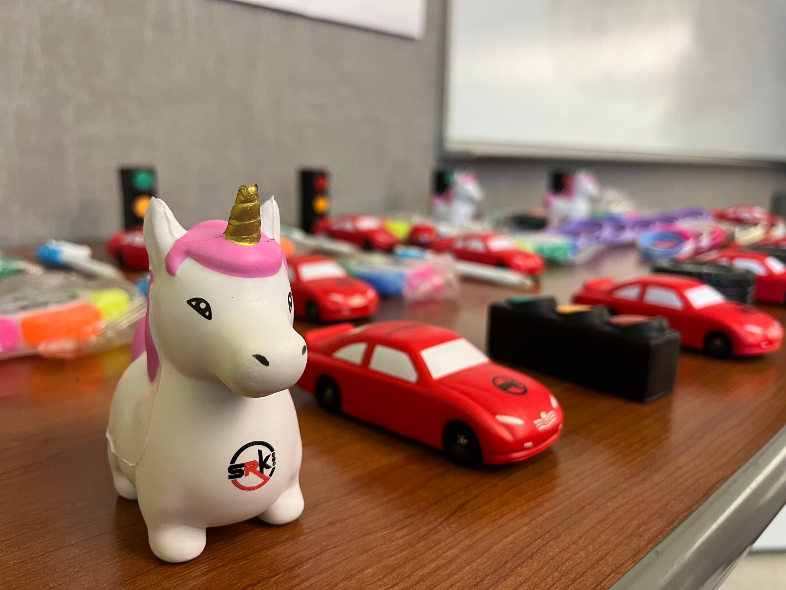 SRK safety giveaways — branded toy cars and traffic-safety items for students