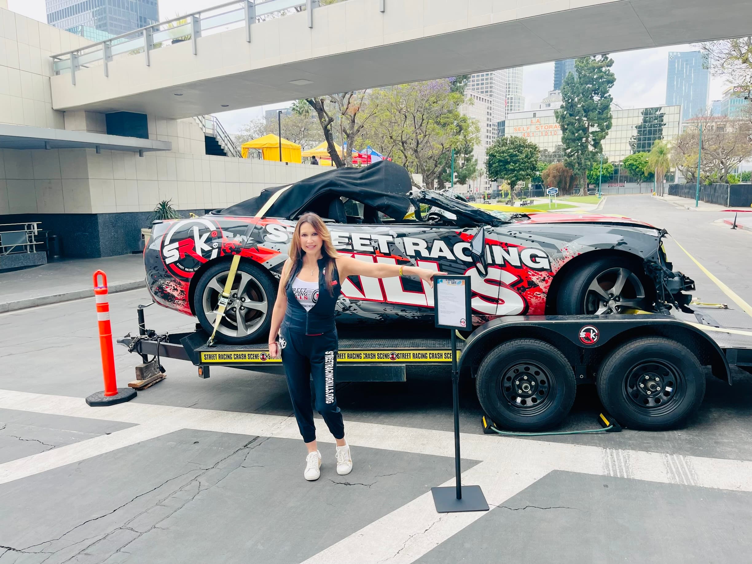SRK crashed-car display with founder Lili Trujillo Puckett at a Los Angeles community event